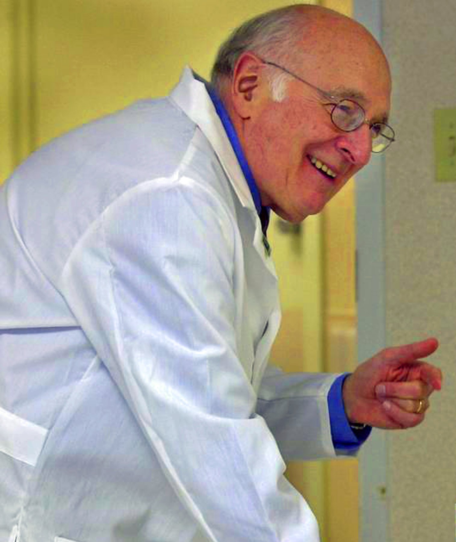 Dr. Lawrence Fishman in a white lab coat, in conversation, smiling and gesturing with his hand.