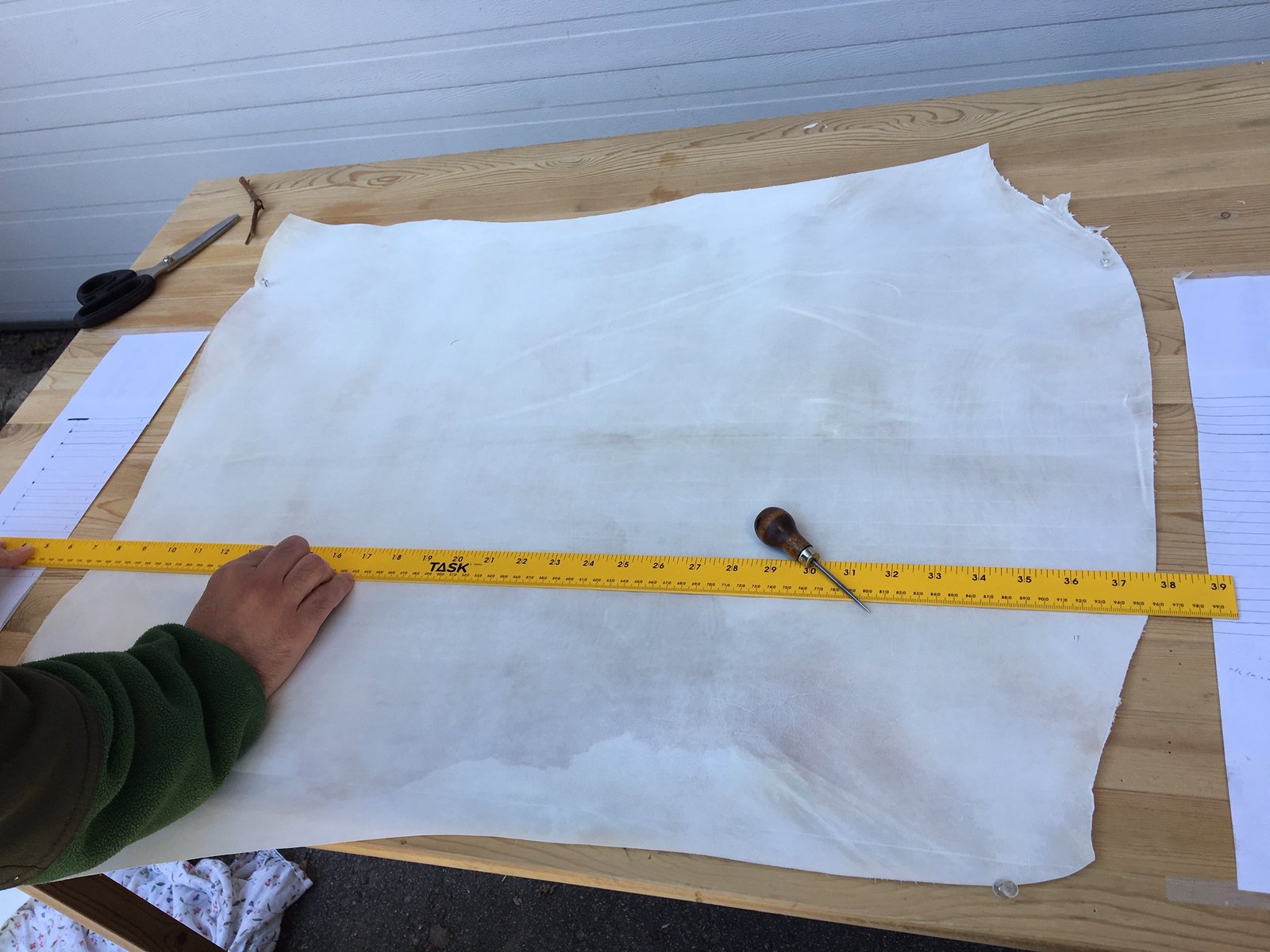 A measuring tape laid across a sheet of fresh parchment.